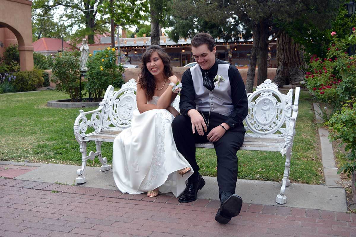 bride and groom sitting on a bench laughing